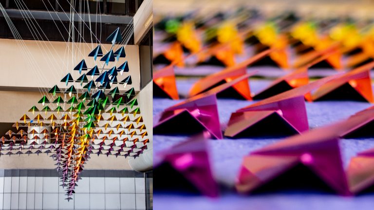 Two images: left image shows a large rainbow-colored metal sculpture of small paper airplanes that together form a large paper airplane; image two shows a close up of several small paper airplanes