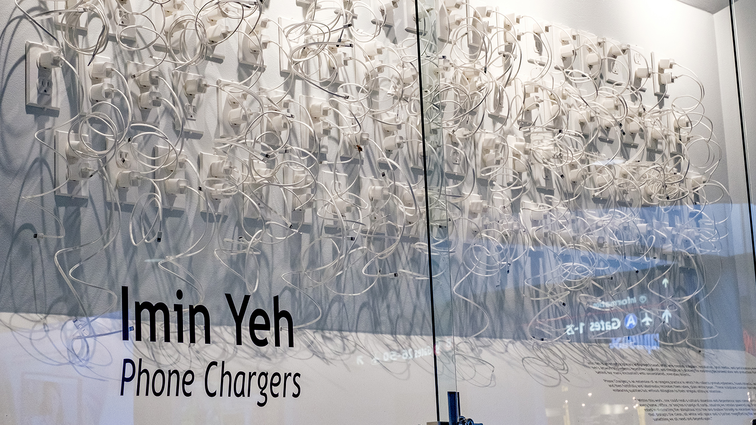 Photograph of an installation of hundreds iPhone chargers constructed from paper plugged into paper outlets