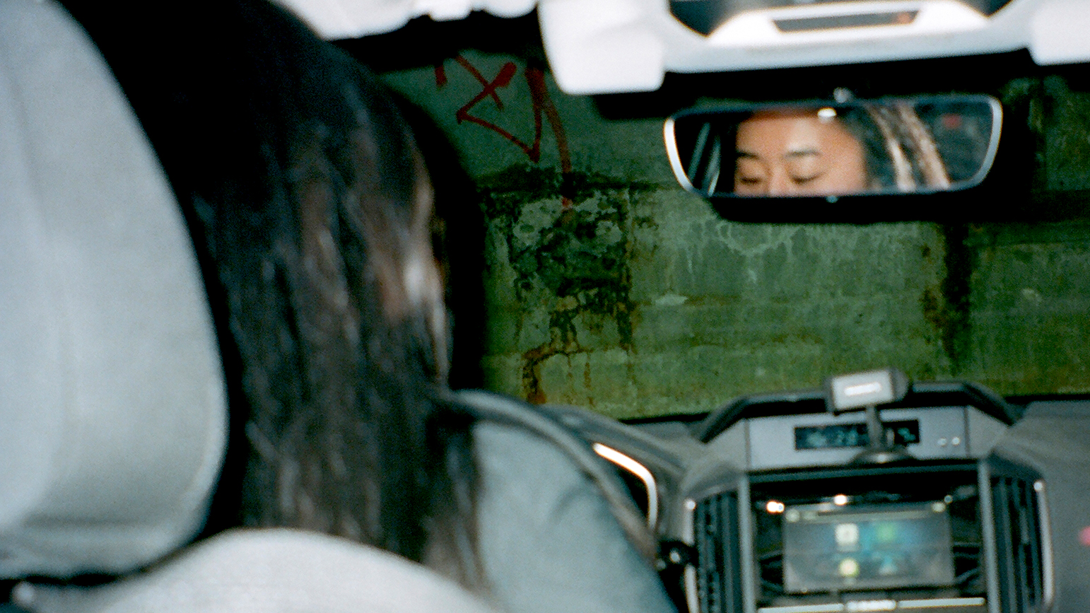Photograph taken from the back seat of a car showing the reflection of the driver's eyes in the rear view mirror