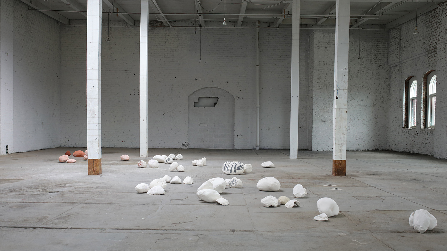 Small ceramic sculptures installed on the floor of an old industrial space