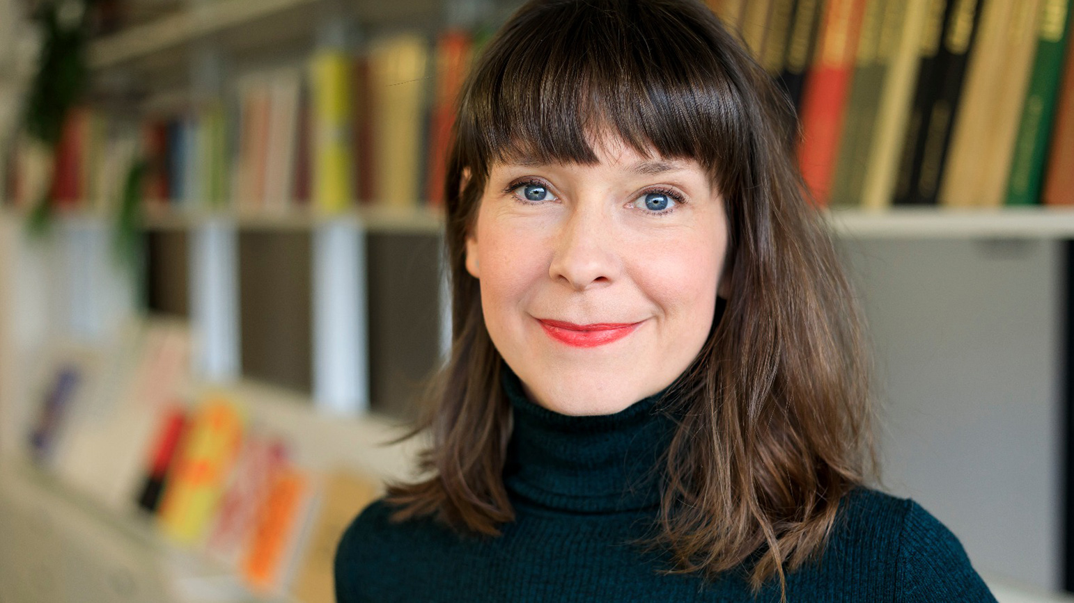 Headshot of a woman with a bookshelf in the background