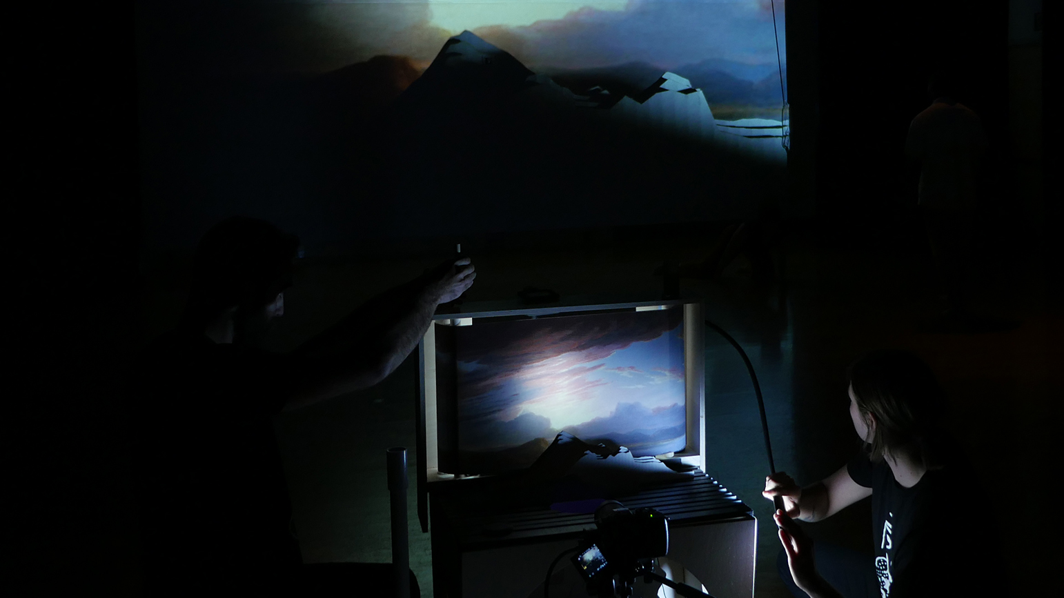 Two people running a projection with a mountain scene