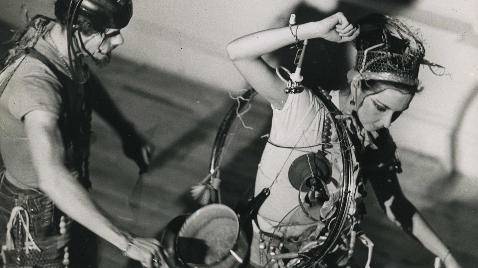 Black-and-white image of two performers with sound making devices attached to themselves