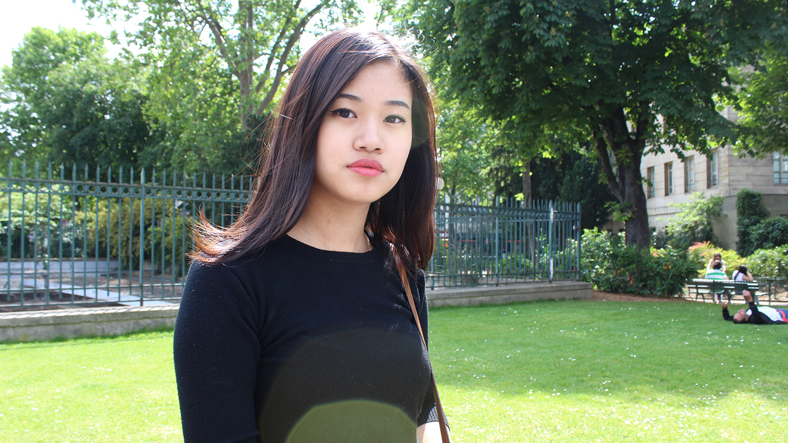 Photograph of Hannah Kim standing outside on a sunny day with a green lawn and trees behind her