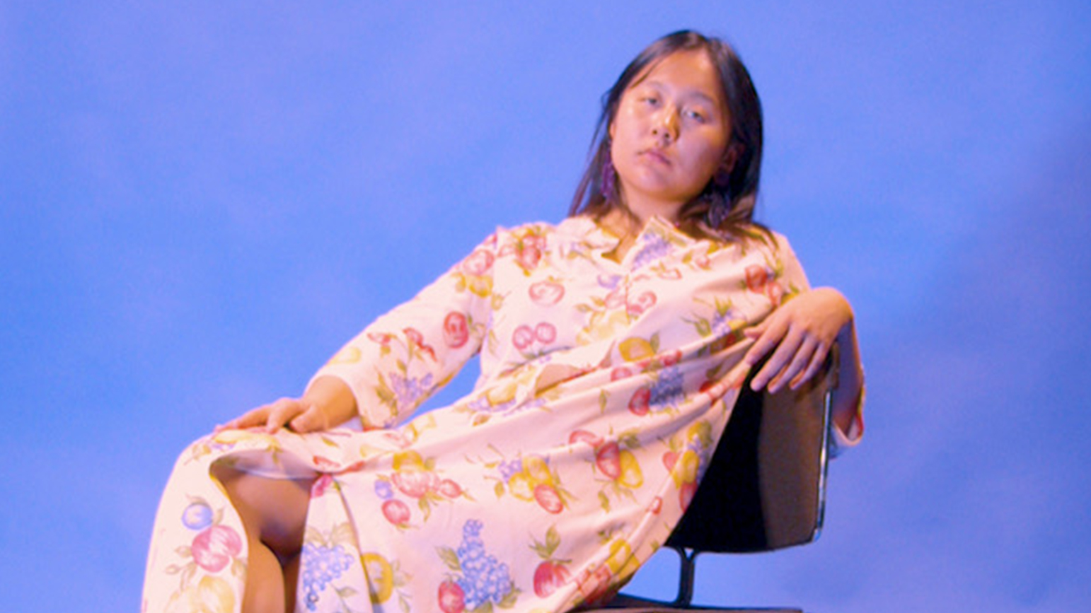 Image of Nana Cheon leaning back in a chair against a blue background