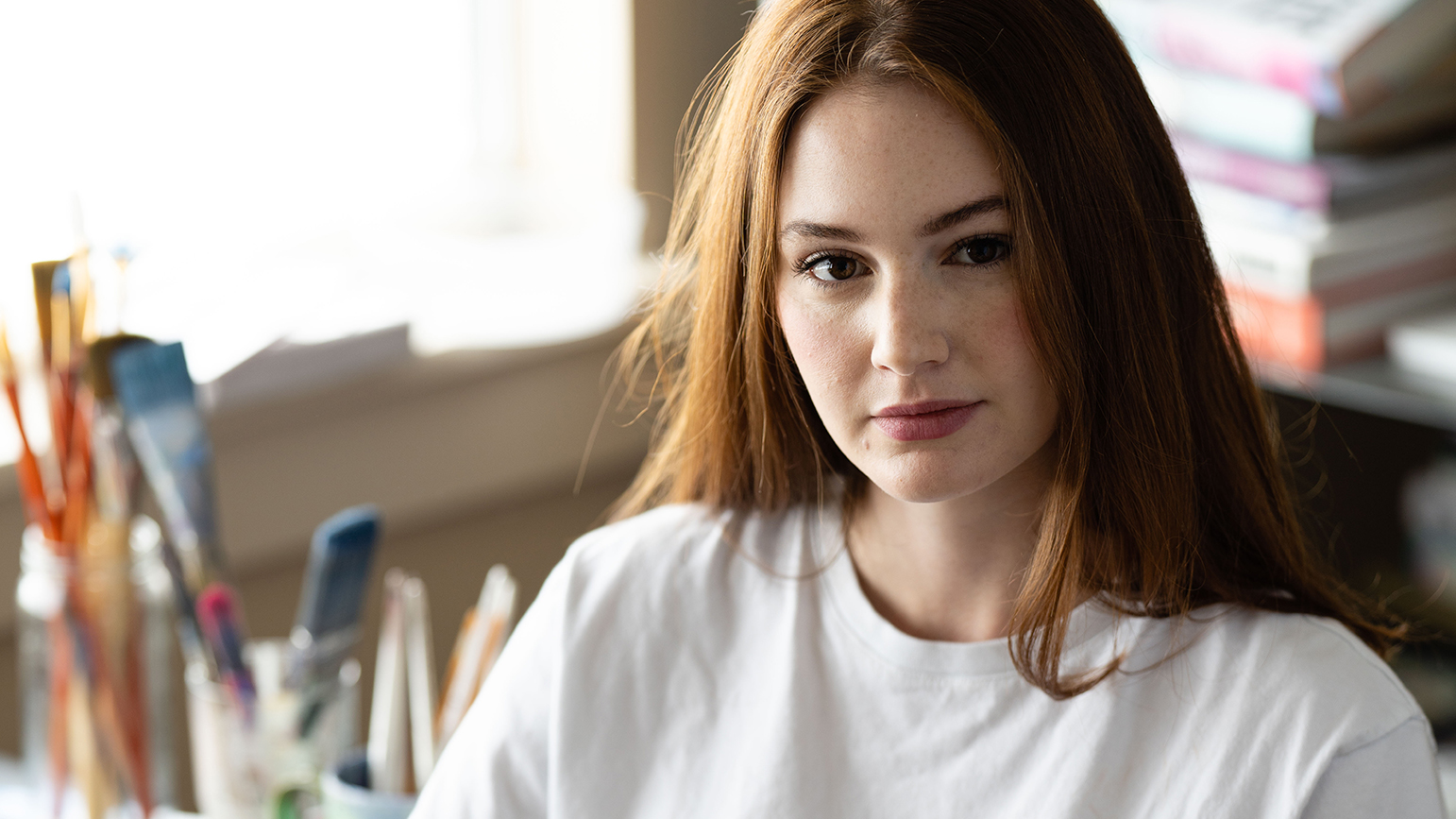 Headshot of Sydney Krantz with her studio behind her