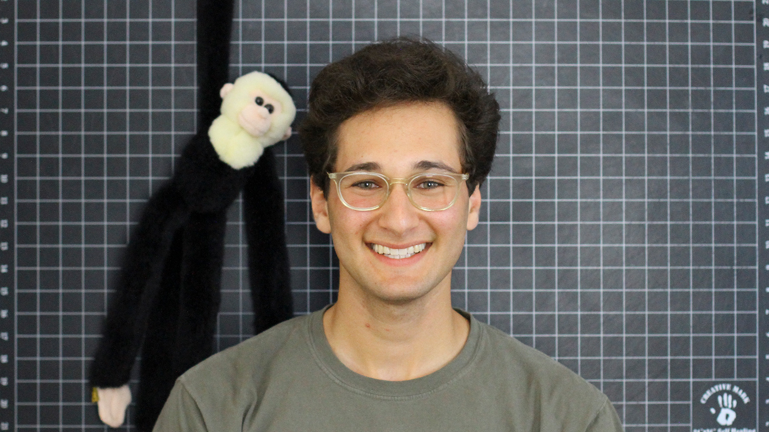 Headshot of Zachary Rapaport in front of a grid mat and with a stuffed monkey